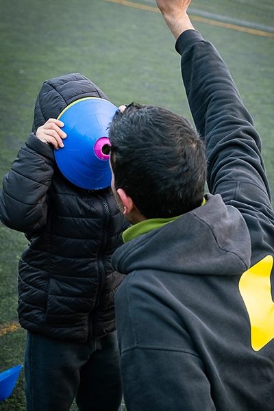 alumno motrinfan jugando con conos junto a su profe
