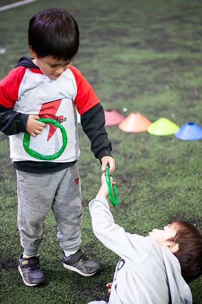 nene con remera motrinfan compartiendo un aro de papel verde con otro nene