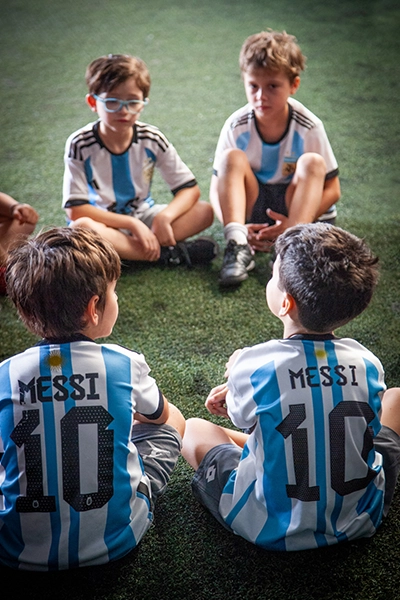 alumnos motringan vestidos para jugar al futbol con la camiseta de argentina de messi sentados en círculo